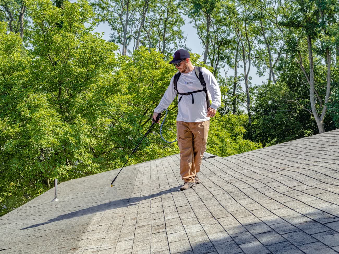 Nano Shield worker on a shingle roof beside a ladder at a Calgary job