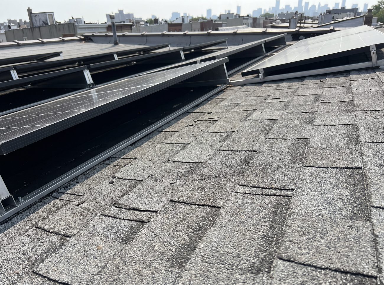 Exposed asphalt shingle surface between and around the rows of a rooftop solar array
